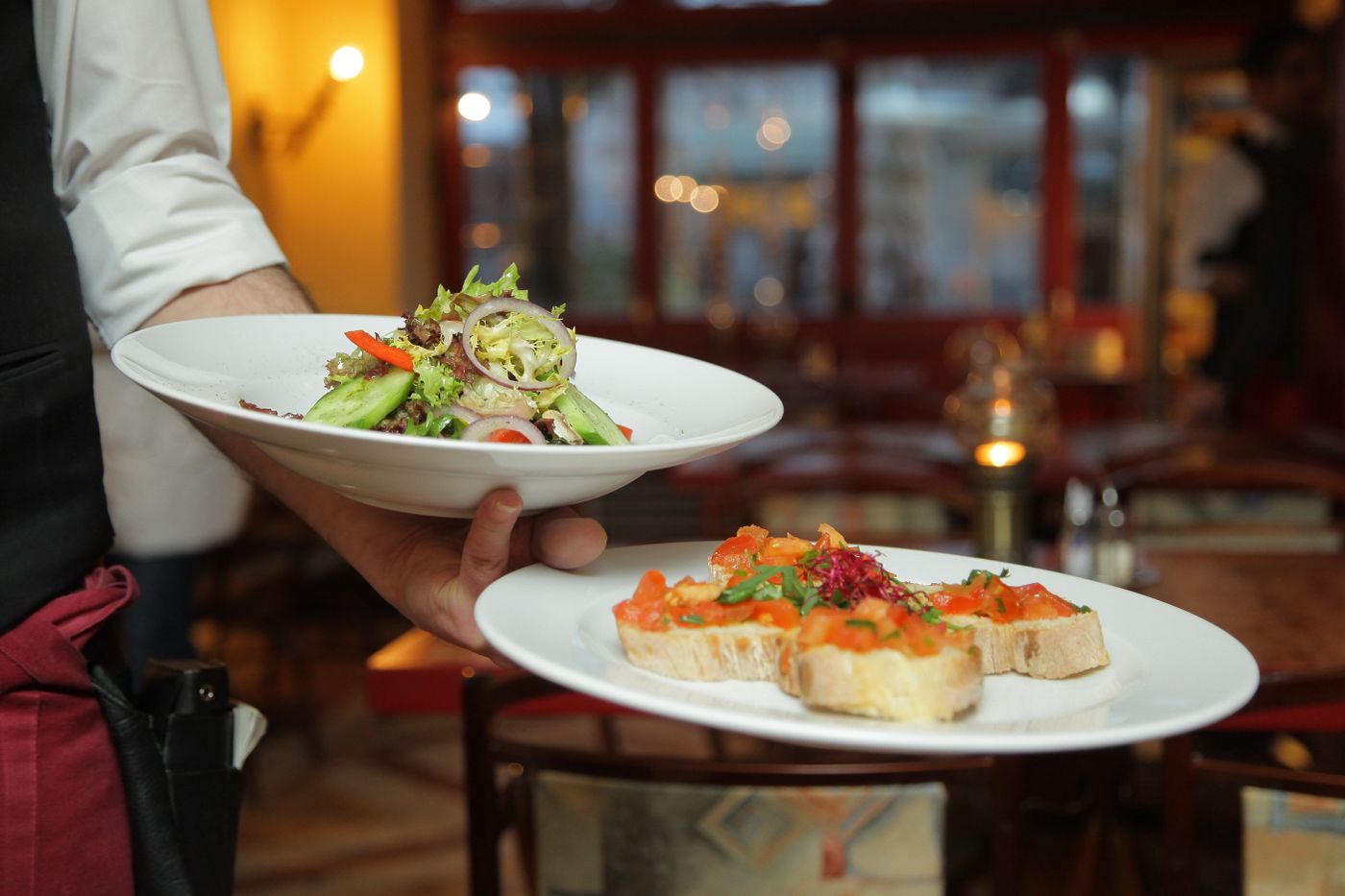 Illustrative restaurant server carrying plates to a table